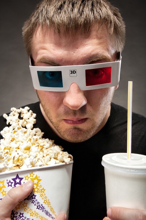 Funny man watching 3D movie, drinking soda and eating popcornの写真素材