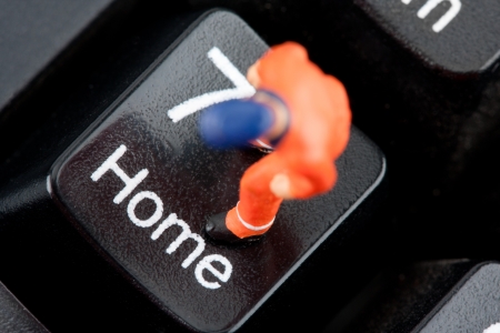 Small figurine of worker standing on computer keyboardの写真素材