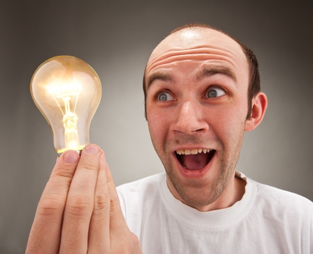 I have an idea! Surprised man holding lighting bulbの写真素材