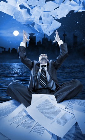 Businessman throwing away papers at night against downtownの写真素材