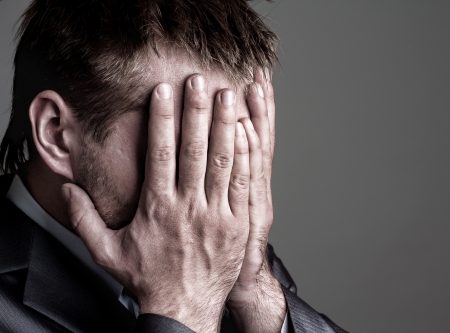 Exhausted sad businessman covering his face by handsの写真素材