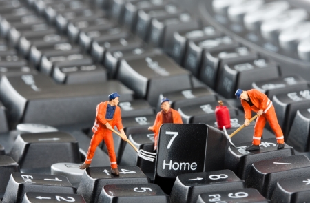 Small figurines of workers repairing computer keyboardの写真素材