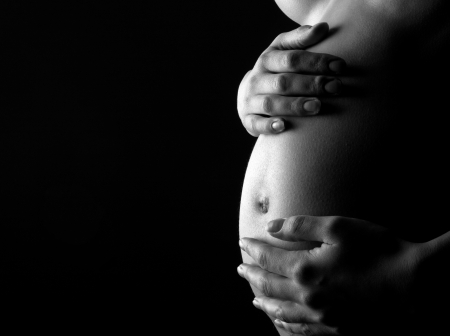 Naked pregnant woman holding abdomen. Waiting for a child