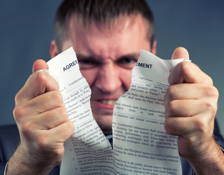 Angry businessman tearing agreement in piecesの写真素材