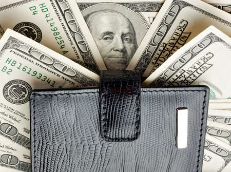 Black leather wallet on heap of moneyの写真素材