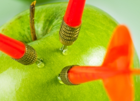 Three red arrows of darts in green apple. Close-upの写真素材