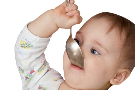 Baby girl holding spoon in mouth. Isolated on whiteの写真素材