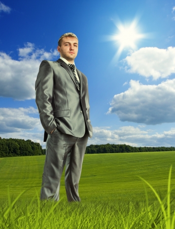 Confident businessman standing on meadow in beautiful dayの写真素材