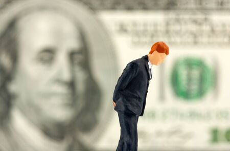 Miniature figurine of loser businessman with $100 banknote on backgroundの写真素材