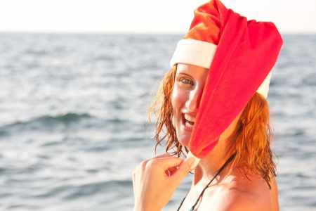 Tan smiling woman in christmas hat in seaの写真素材