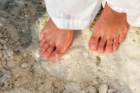 Woman in white walking barefoot on the beachの写真素材