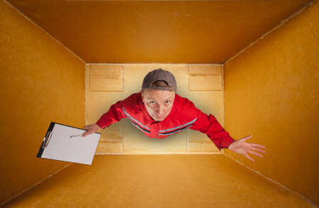 Sad mail courier with clipboard inside empty boxの写真素材