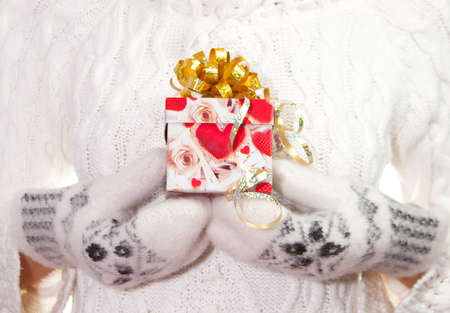 Red christmas gift with bow in palms of handsの写真素材