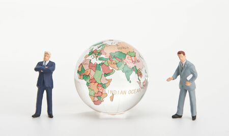 Figurines of two businessmen and glass globeの写真素材