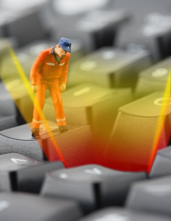 Figurine of worker looking into pit in computer keyboard