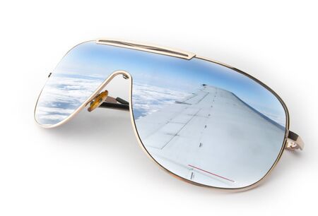 Travel concept - reflection of a blue sky and plane wing in sunglasses