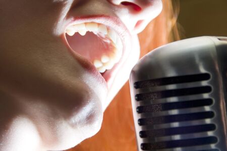 Woman singing into retro microphoneの写真素材