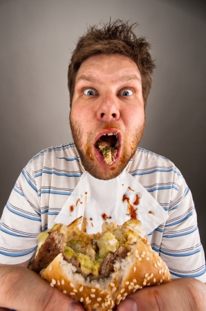 Portrait of surprised dirty man chewing hamburgerの写真素材