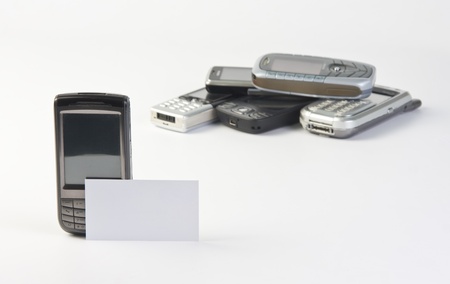 Mobile phone with contact business card and heap of phones in backgroundの写真素材