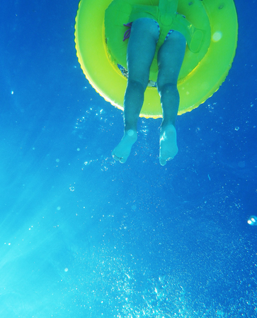Little girl with yellow buoy swimming in poolの写真素材