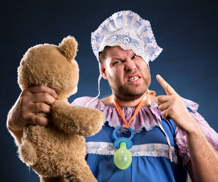 Angry man with toy bear in studioの写真素材