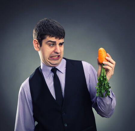 Small carrot in hands of a businessmanの写真素材