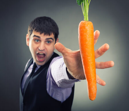 Man trying to reach fresh carrotの写真素材