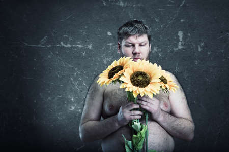 Portrait of sad man holding sunflowers, studio shootの写真素材