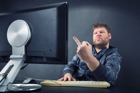 Fat angry man sitting at desk looking at monitor  screenの写真素材