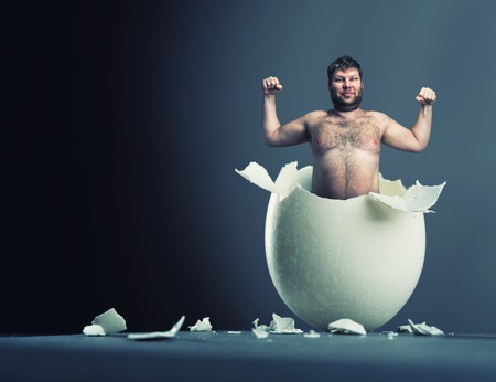 Close-up picture of broken egg with man isolated on gray backgroundの写真素材