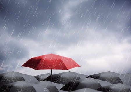 Black and one red umbrellas under rain and thunderstormの写真素材