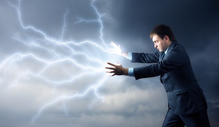 Young man with lightnings from his hands over cloudsの写真素材
