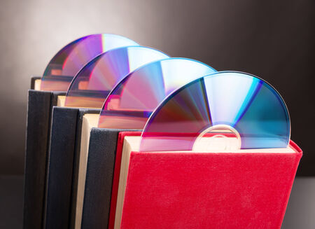 Four cd disks are sticks out from red bookの写真素材