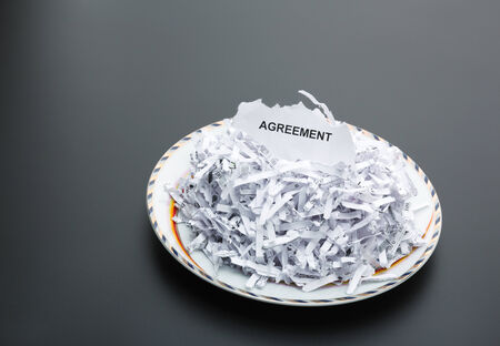 Plate of heap of white shredded papers and paper with agreementの写真素材