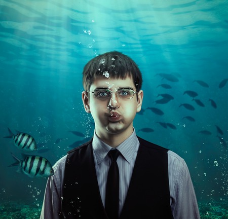 Underwater scene of a businessman with fishes, business conceptの写真素材