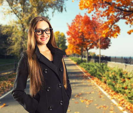 Beautiful woman in autumn park with red foliageの写真素材