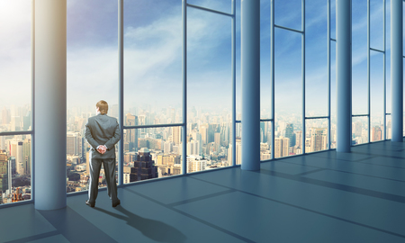Businessman standing in the office and looking at the skyの写真素材