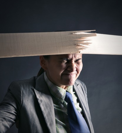 Woman breaks wooden stick by her headの写真素材