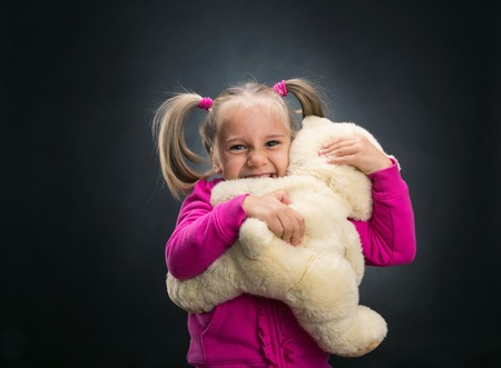 Little cute girl holds toy bear on greyの写真素材
