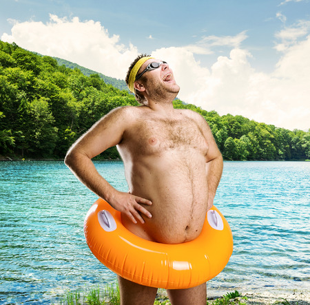 Strange naked man with children\'s buoy on the lakeの写真素材