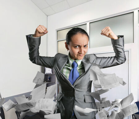Powerful business woman with fists in the officeの写真素材