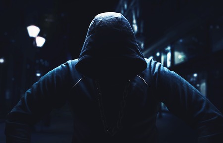 Angry man, sitting with a hood on in the street