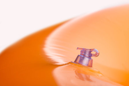 Inflatable orange bath cushion with closed valve isolated on whiteの写真素材