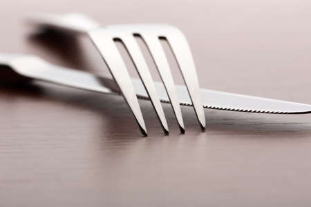 Closeup of fork and knife on wooden background