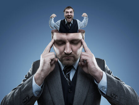 Crazy man in the head of young businessman on blueの写真素材