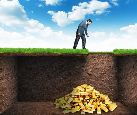 Businessman bends and looks at the treasure in the soilの写真素材