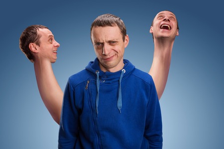 Concept of split personality, a man with three heads over blueの写真素材