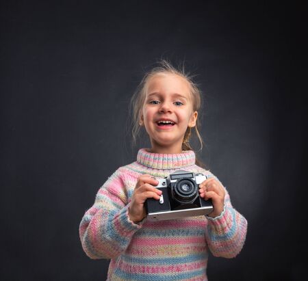 Happy little girl with retro camera on greyの写真素材