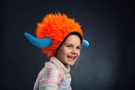 Little funny girl in party hat over dark backgroundの写真素材