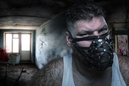 Adult agressive man in muzzle in bloody roomの写真素材